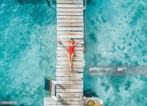 Aerial shot of womann relaxing in a water bungalow